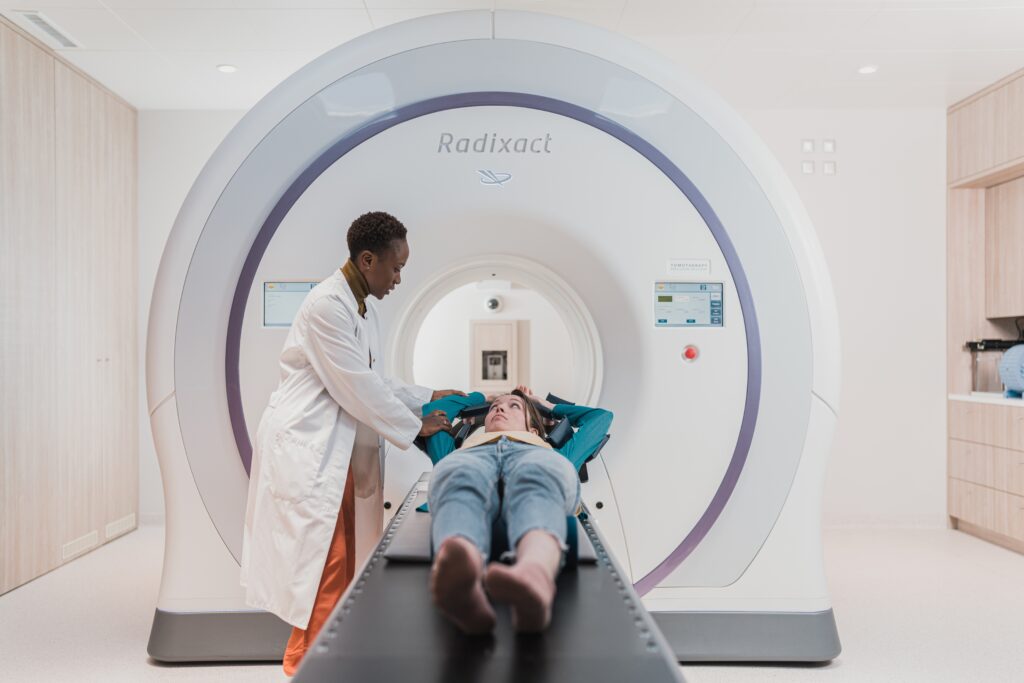 Medical doctor assisting patient as they lie down for a CAT scan. This image is representative of the topic of article, which is the cost of primary doctor visit without insurance.